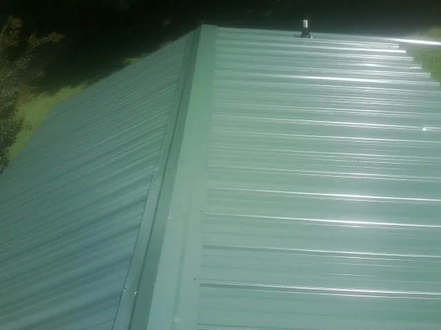 New green metal panels meeting at the ridge of a roof — Flat Roof Repair work by our crew in Fremont