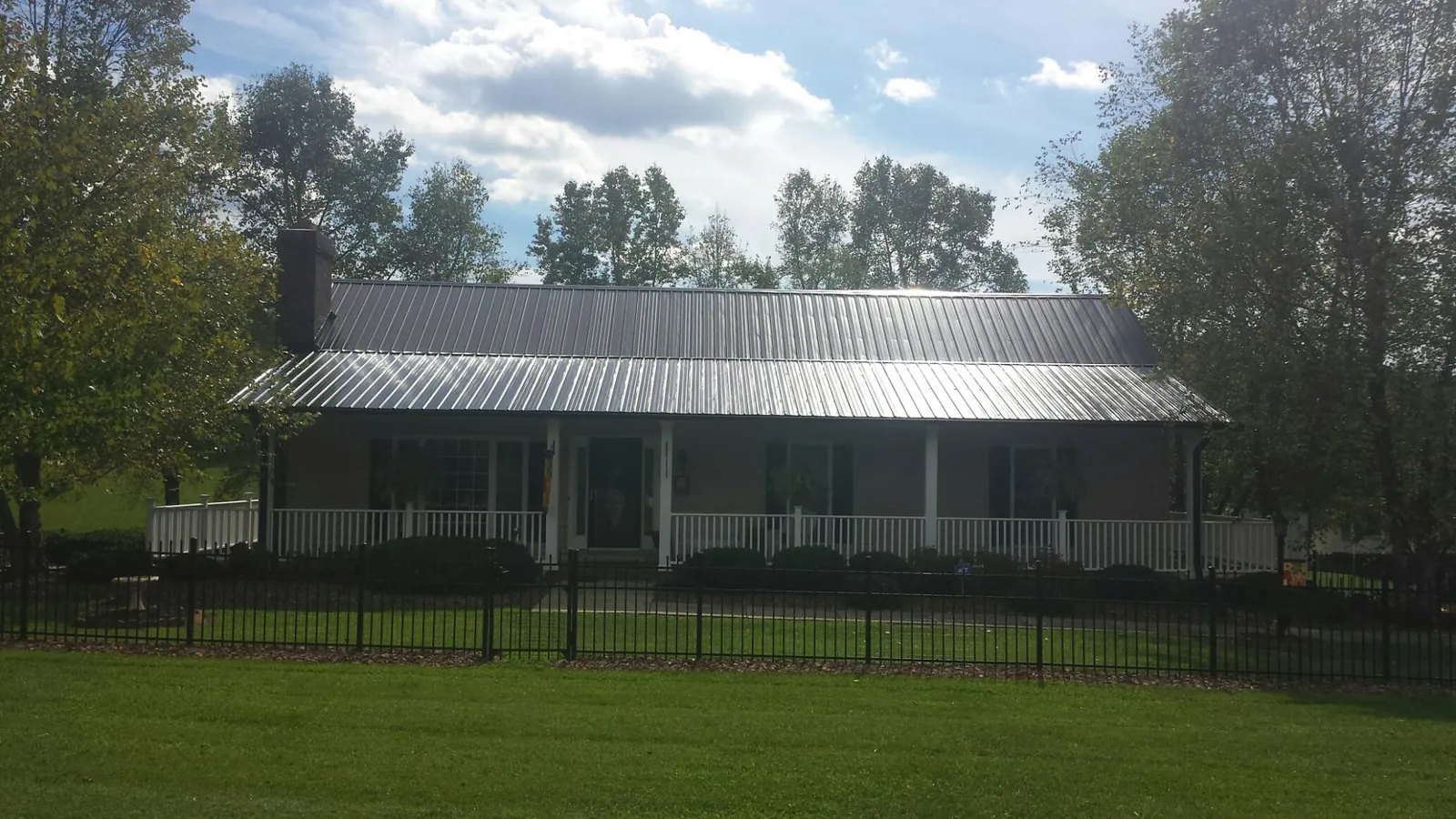 Gray metal roof on a brick ranch with a full width front porch — Gutter Guard Installation work by our crew in Fremont